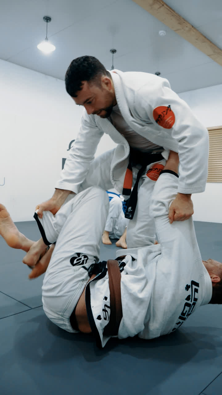 Gi training: a student on their back controlling a standing partner