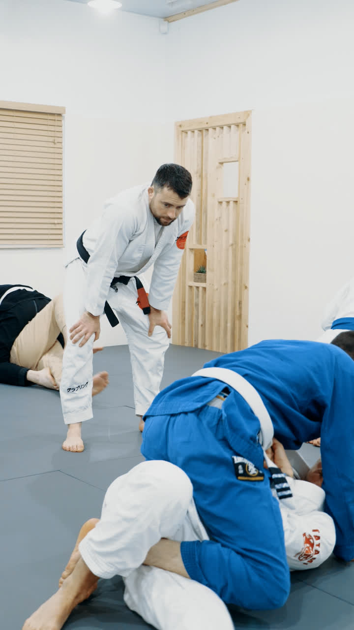 Black belt instructor watching students drill in the gi