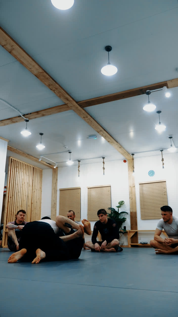 Members sitting around the mat watching a technique demonstration